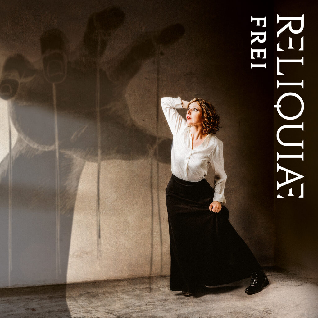 Das Cover der neuen Single "FREI" von RELIQUIAE zeigt die Geigerin der Band, Svea, verängstigt auf einen Bedrohlichen Schatten einer Puppenspieler-Hand blickend.